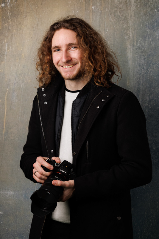 Portrait d’un homme souriant avec un appareil photographique dans les mains